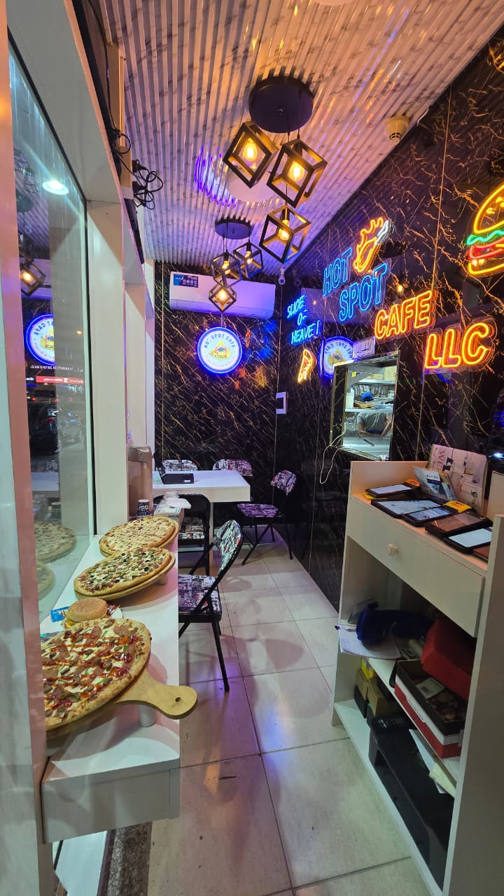 Inside Hot Spot Cafe with neon lights and fresh pizzas on display